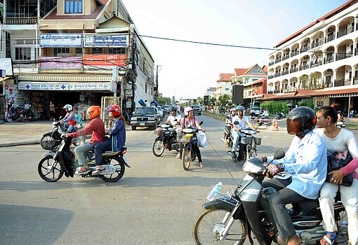 Blick auf eine Geschäftsstraße mit modernen Bauten und vielen Mopeds