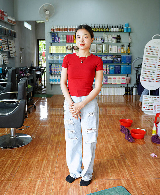 Eine junge Asiatin mit rotem T-Shirt in einem Friseursalon