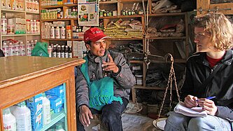 Shreeram KC sitzt mit Besuch aus Deutschland im Projektgebiet zusammen