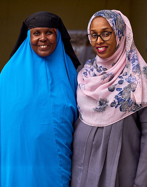 Ein Netzwerk von Aktivistinnen in Somaliland setzt sich gegen Gewalt an Frauen ein. Zwei Frauen stehen vor einem Konferenztisch und lächeln in die Kamera.