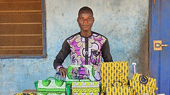 Junger Mann steht vor einem Tisch mit selbstgemachten Gegenständen