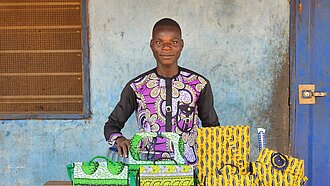 Junger Mann steht vor einem Tisch mit selbstgemachten Gegenständen