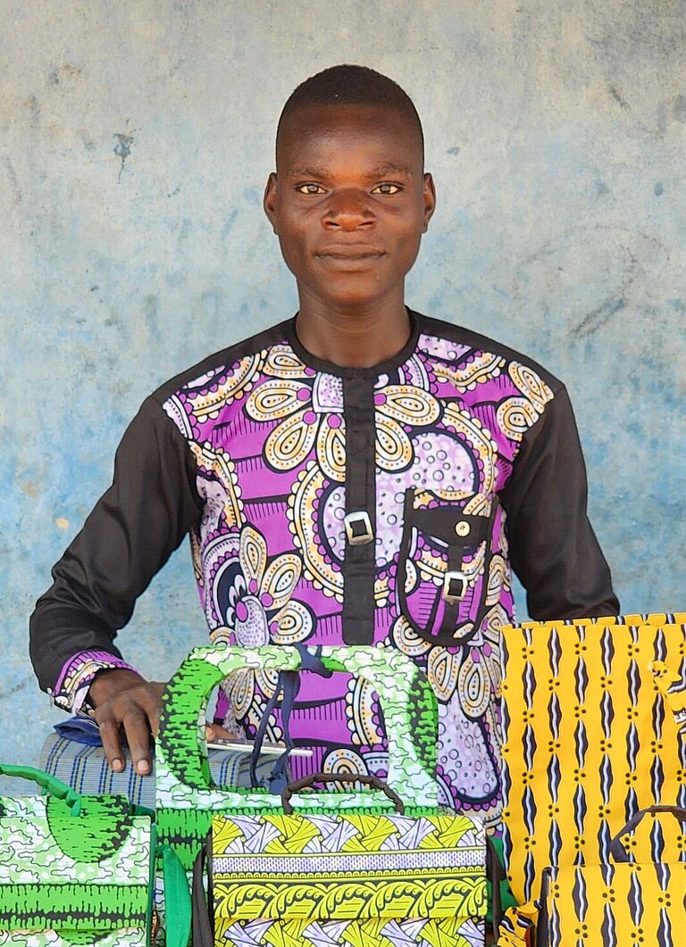 Junger Mann steht vor einem Tisch mit selbstgemachten Gegenständen