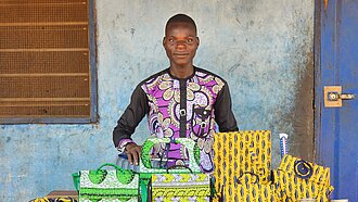 Junger Mann steht vor einem Tisch mit selbstgemachten Gegenständen