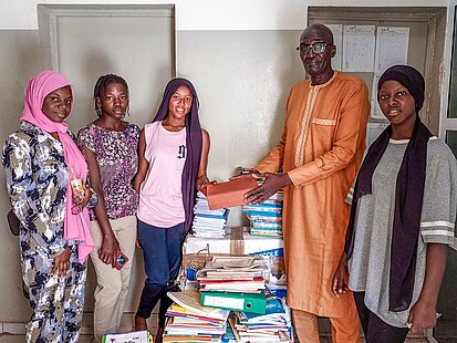 Drei Frauen nehmen Schulmaterialien entgegen