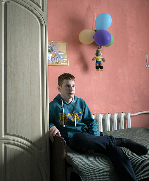 Ein 15-jähriger Junge sitzt auf einem Bett