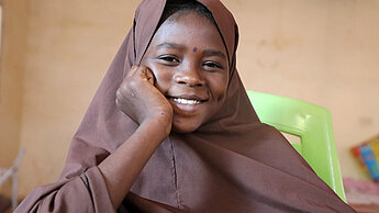 Die 12-jährige Roukaya lächelt in die Kamera. Sie trägt ein braunes Kopftuch.