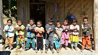 Mehrere kleine Kinder aus Laos stehen in einer Reihe und waschen ihre Hände.