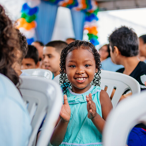 Ein kleines Mädchen klatscht lächelnd in die Hände