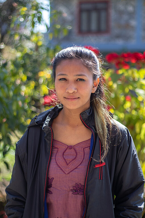 Urmila aus Nepal Eine junge Frau steht in Jacke draußen und schaut in die Kamera