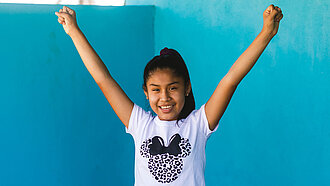 Bild: Ein Mädchen aus Peru, das ihre Arme fröhlich in die Luft streckt
