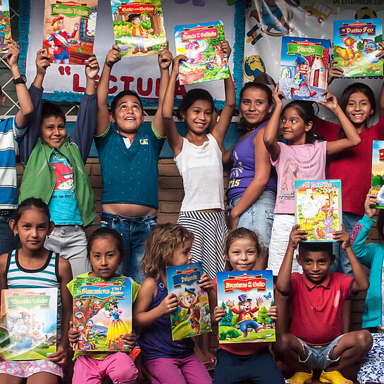 Kindergruppe halten bunte Bücher hoch.