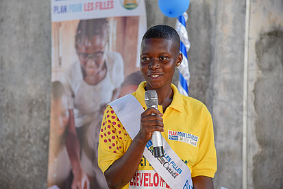Eine junge Frau spricht bei einer Veranstaltung in ein Mikrofon