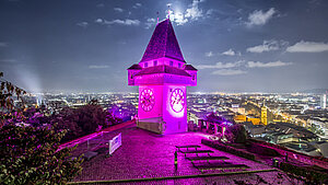 Der Grazer Uhrturm ist nachts Pink erleuchtet.
