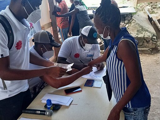 Bedürftige Familien in Haiti erhalten nach Schulungen Bargeldauszahlungen. An bedürftige Haitianer wird Geld verteilt.
