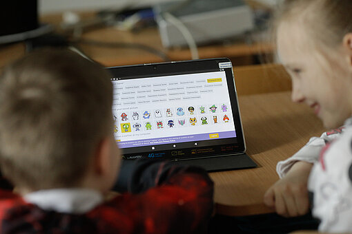 Ein Junge und ein Mädchen sitzen vor einem Tablet Ein Junge und ein Mädchen sitzen vor einem Tablet