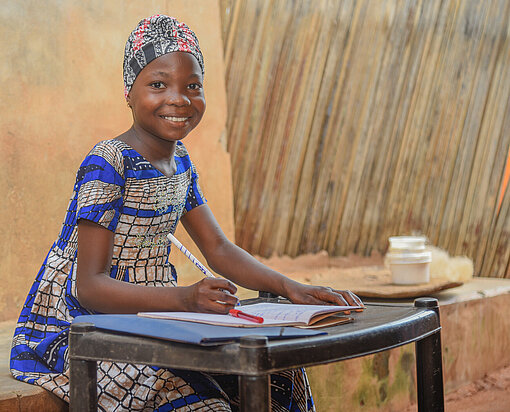Anne sitzt an einem Tisch und schreibt