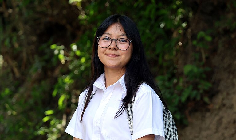 Adriana steht draußen in ihrer Gemeinde in El Salvador