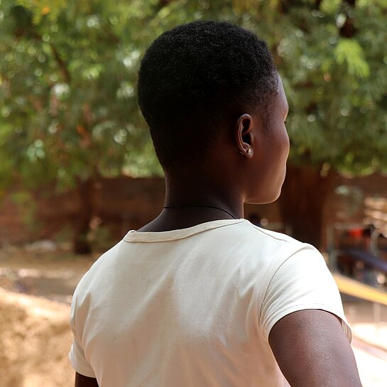 Aline steht draußen in ihrer Gemeinde in Burkina Faso 
