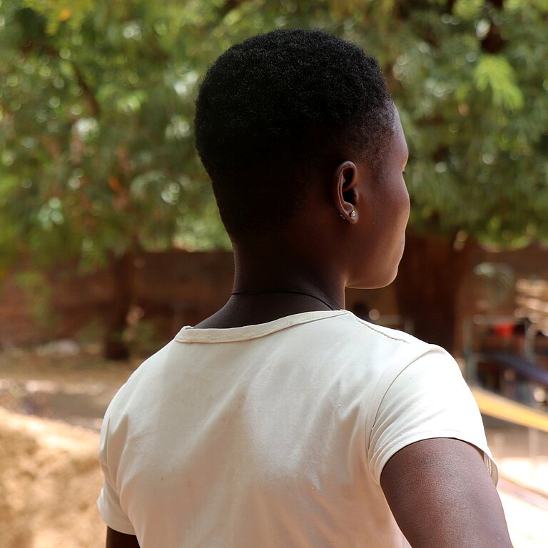 Aline steht draußen in ihrer Gemeinde in Burkina Faso 