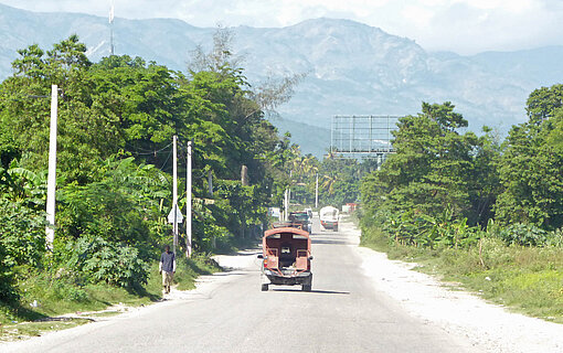 Über die Fernstraße No.2 rollt im Regelfall der Verkehr von Port-au-Prince in den Westen und Süden Haitis. Sie wird aktuell von bewaffneten Banden kontrolliert Eine schmale Teerstraße zwischen Palmen
