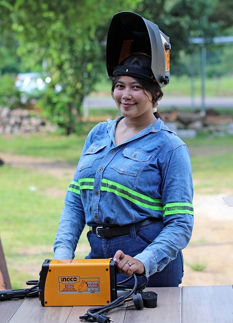 Lizzy mit Helm am Schweißgerät