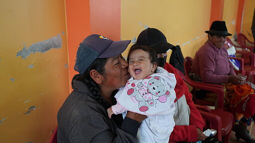 Eine Mutter gibt ihrem Baby einen Kuss auf die Wange.