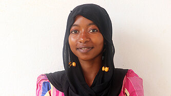 Ein Mädchen mit Kopftuch lächelt in die Kamera