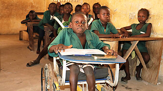 Ein Junge im Rollstuhl sitzt ganz vorne in einer Schulklasse