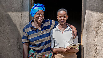 Proby und Ihre Mutter stehen Arm in Arm vor ihrem Haus in Ruanda