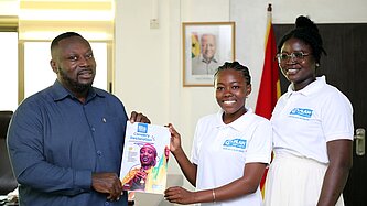 Zwei jugendliche Mädchen übergeben eine ausgedruckte Deklaration an einen Mann