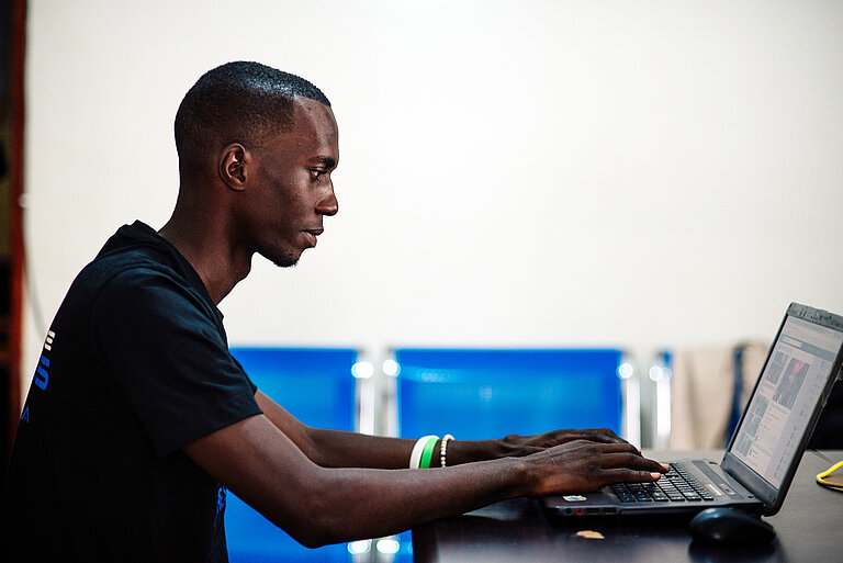 Emmanuel von der Seite vor seinem Laptop. 