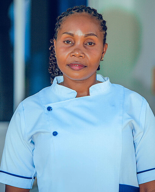 Eine Frau mit hellblauer Bluse schaut in die Kamera