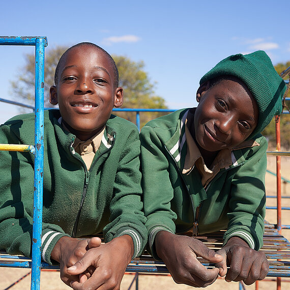 Zwei Jungen in Schuluniformen posieren auf einem Klettergerüst