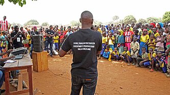 Ein Mann steht vor einer Gruppe ehemaliger Kindersoldaten und spricht über die Gefahren dieser missbräuchlichen Praktik