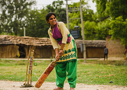 Ein Mädchen in Indien spielt Cricket