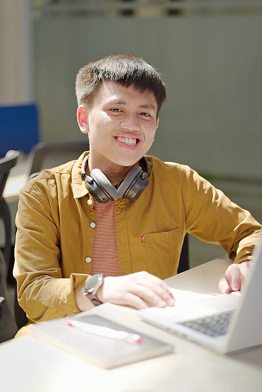 Kevin aus Indonesien arbeitet als IT-Ingenieur Ein junger Mann sitzt erwartungsvoll bereit