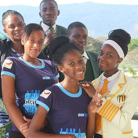 Mädchen vor Kinderheirat schützen in Simbabwe Eine Gruppe junger Jungen und Mädchen tragen T-Shirts von Plan International und gucken glücklich in die Kamera.