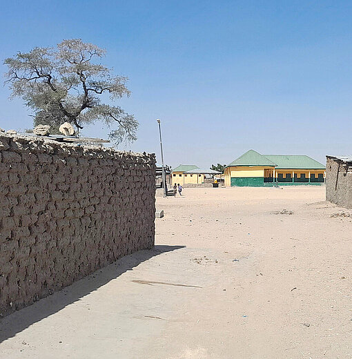 Gleißendes Sonnenlicht strahlt auch erdige Gebäude und eine Lehmmauer