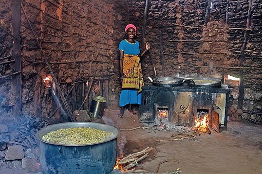 Khadijah ist eine der freiwilligen „Lunch Ladies“ im Bezirk Kilifi Eine Frau schürt Feuer unter riesigen Kesseln an