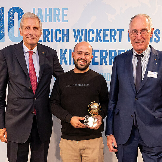 Drei Männer nehmen Preis entgegen.