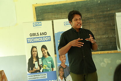 Ein Mann spricht vor einem Plakat zur Förderung von Mädchen und Technik