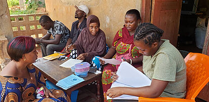 Menschen sitzen um einen Tisch und blättern in Dokumenten