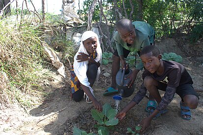 Jugendliche gießen ein Gemüsebeet