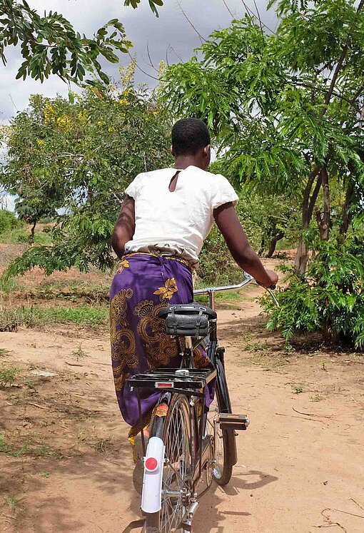 Nester (26) radelt zu abgelegen lebenden Klientinnen im Bezirk Kasungu Eine Frau rollt mit dem Rad auf und davon