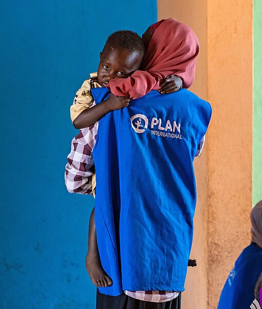 Eine Frau trägt einen kleinen Jungen auf ihren Armen