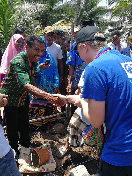 Björn Klüver bei einem von Plan international organisierten Hilfsprojekt. Björn Klüver gibt einem Mann die Hand.