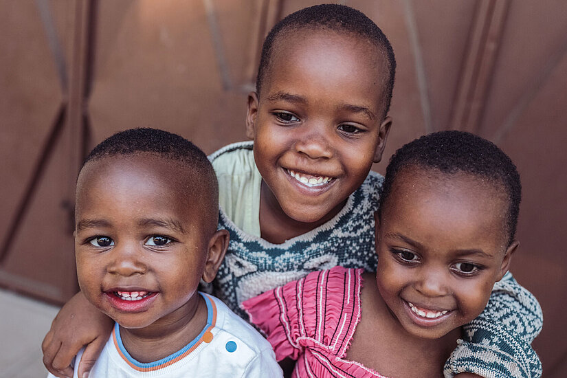 Bild: Drei kleine Kinder grinsen in die Kamera