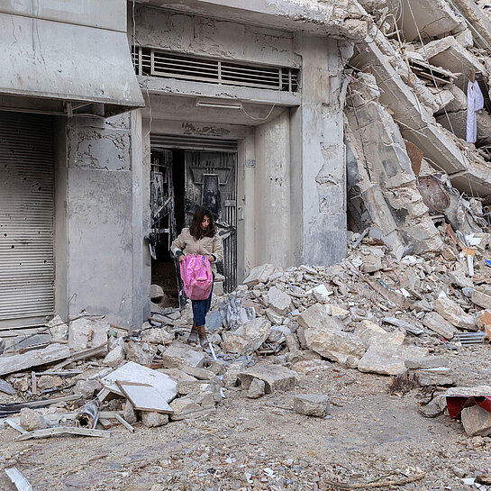 Eine Frau holt eine Tasche aus den Trümmern eines Gebäudes