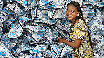 Eine Frau steht vor einem Berg Trashy Bags.